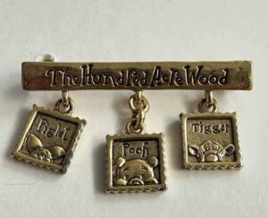 Pooh with Piglet and Tigger hanging under the Hundred Acre Woods sign pin