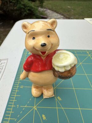 Vintage Disney ceramic figurine of Winnie the Pooh holding a honey pot