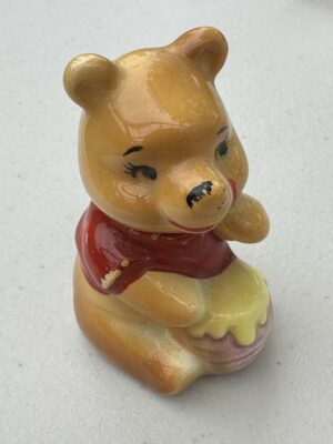 vintage ceramic figurine of Winnie the Pooh holding a honey pot