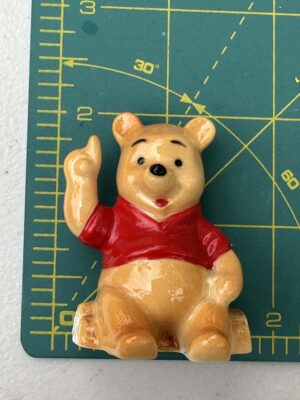 Pooh figurine sitting on a log