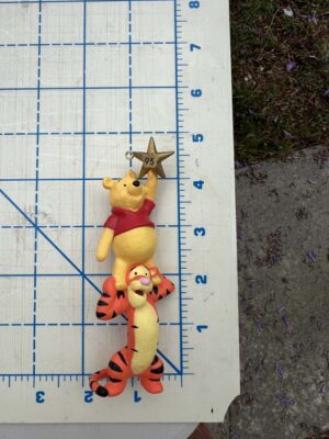 Pooh standing on Tigger's Shoulders holding a star ornament